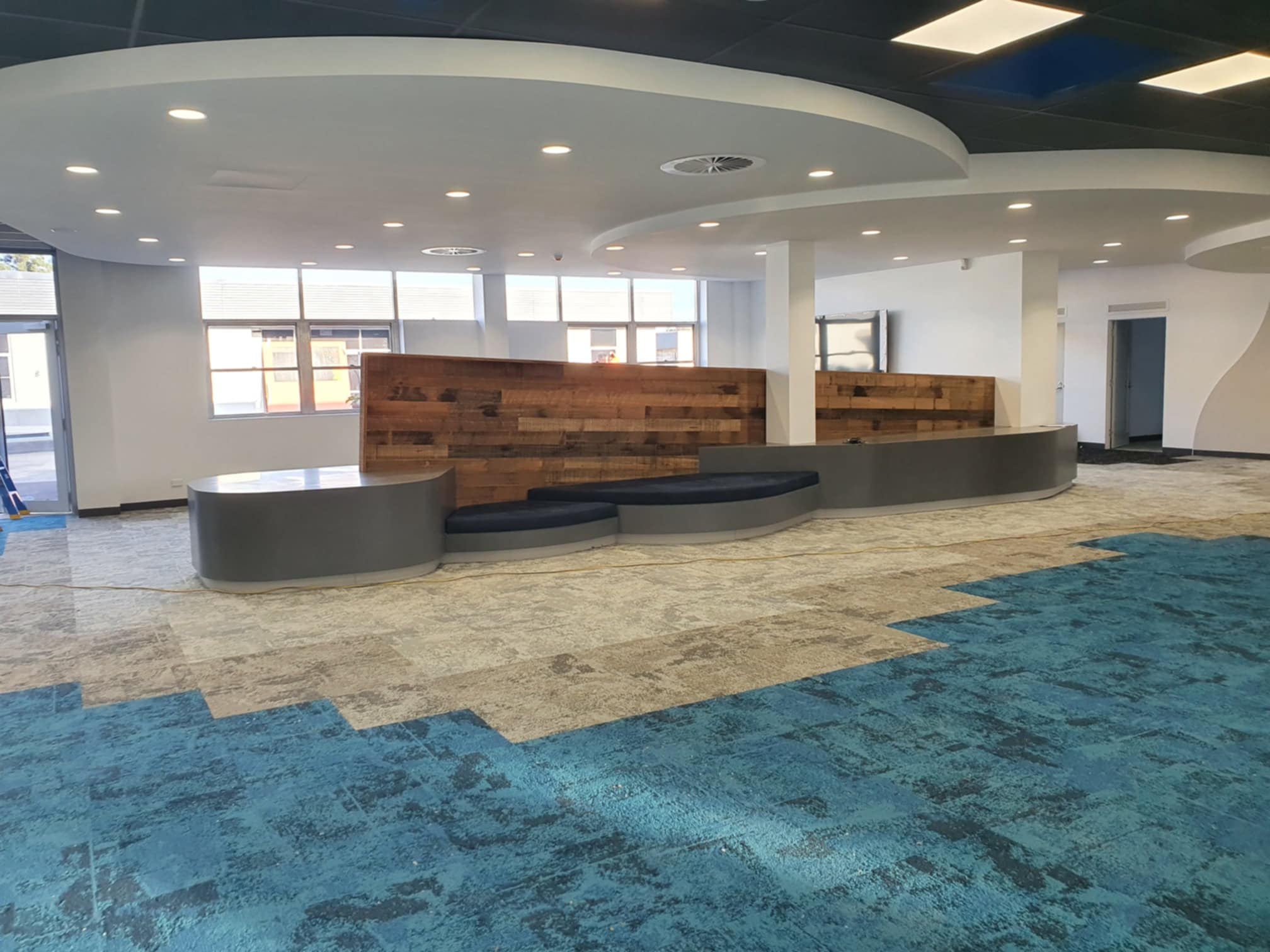 Commercial foyer fitout with a curved bulkhead ceiling and timber feature wall, painted by BPM Group